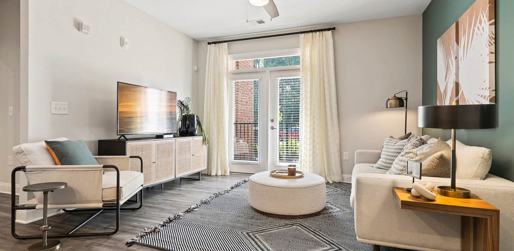 Hawthorne Waterstone apartment living room with wood flooring and a large patio door furnished with a TV stand, chair, couch, and coffee table