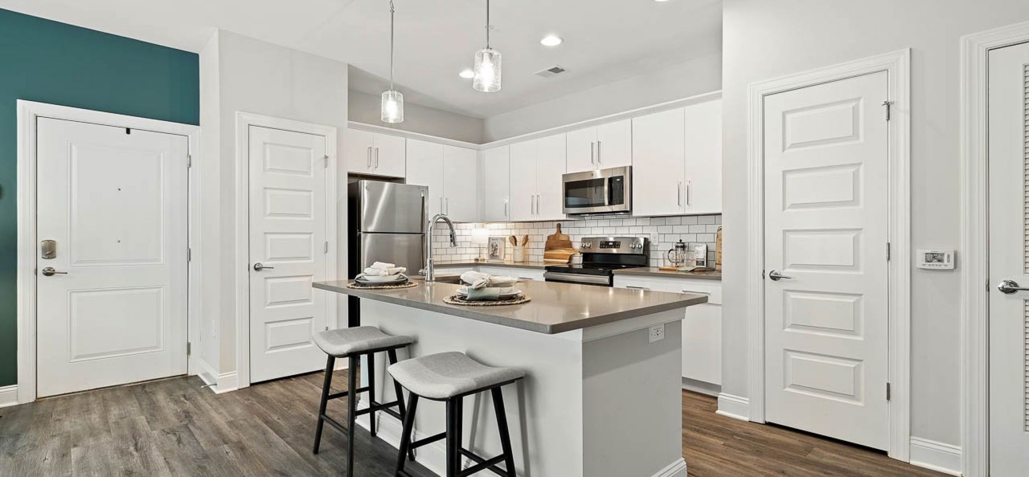 Hawthorne Waterstone apartment kitchen interior with kitchen island, stainless steel appliances, and white cabinetry
